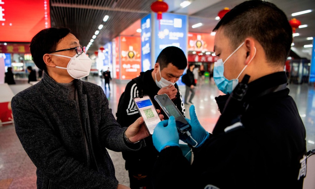 Uma pessoa usando máscara mostra um QR code verde no seu celular para informar seu estado de saúde a um segurança em uma estação de trem em Wenzhou, China. Foto: Noel Celis/AFP via Getty Images
